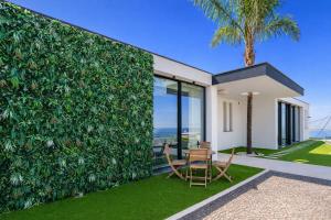 a living wall with a table and chairs in front of a house at Luxury Ocean View Villa I Swimming pool I Vincents Place in Estreito da Calheta