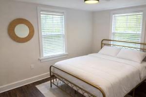 a white bedroom with a bed and two windows at The Downtown Cedar in Ocean Springs