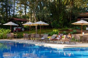 two people sitting on chairs next to a swimming pool at Grinbergs Village Hotel in Socorro