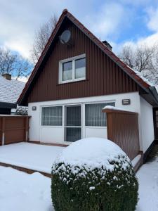 a red house with snow on the driveway at Haus Ostseewind in Zingst