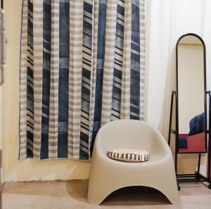 a white chair sitting in front of a curtain at Sela Stay Prawirotaman in Yogyakarta