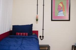 a bedroom with a blue bed and a painting on the wall at Sela Stay Prawirotaman in Yogyakarta