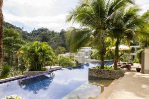 a swimming pool with two palm trees and a building at Kamala Hills Serviced Apartments in Kamala Beach