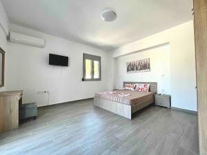 a bedroom with a bed and a flat screen tv at Nóstos Home in Kos