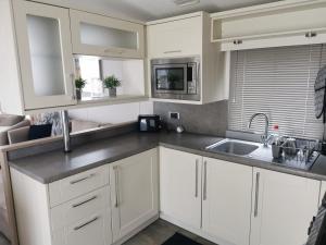 a kitchen with white cabinets and a sink at Washbrook Way 2 in Fenny Bentley