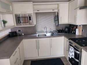 a kitchen with white cabinets and a sink at Washbrook Way 2 in Fenny Bentley