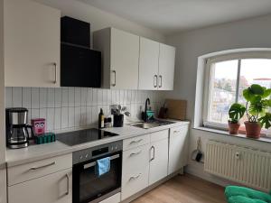 a kitchen with white cabinets and a sink and a window at Zum alten Pasewalker Kaufmann in Pasewalk