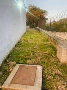 a drain in the grass next to a wall at Lubelo Close in Mbabane +1 photo