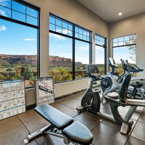 a gym with treadmills and ellipticals in a room with windows at Desert Rose Resort & Cabins in Bluff