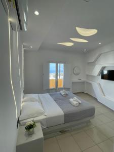 a white bedroom with a bed and a window at Fira centerline Prestige suites in Fira