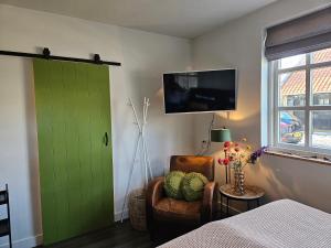 a bedroom with a green door and a chair and a bed at 't Rheebokje in Uddel