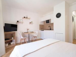a white bedroom with a small table and a kitchen at Le doux refuge domaine thermal et activités touristiques Amnéville in Amnéville