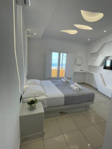 a white bedroom with a bed and a window at Fira centerline Prestige suites in Fira +84 photos