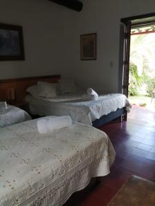 ein Zimmer mit drei Betten, die mit weißen Laken bezogen waren in der Unterkunft die sonne in Estación El Salto