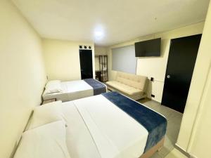 a hotel room with two beds and a couch at Hotel Estadio 80 in Medellín