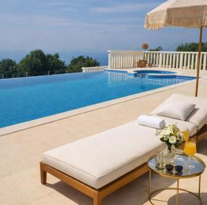 a couch and an umbrella next to a swimming pool at Villa Conte in Podstrana