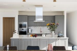 a kitchen with gray cabinets and a white counter top at Taigh Rona in Tarbert