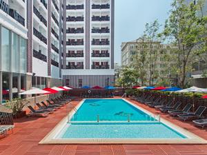 
a pool with chairs and umbrellas in the middle of it at Ibis Pattaya - SHA Extra Plus in Pattaya
