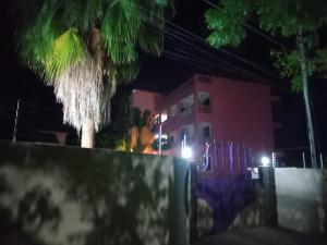 a palm tree in front of a pink building at night at TN Apartments deviat in Diani Beach