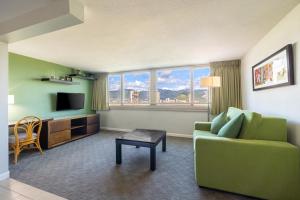a living room with a green couch and a television at Skyline Island Colony Hotel in Honolulu