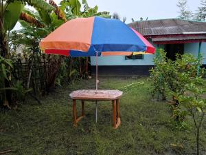 a table with a colorful umbrella on the grass at Bonolota Eco Villa in Mongla