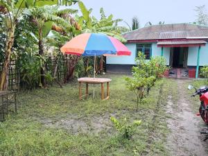 a table with a colorful umbrella in front of a house at Bonolota Eco Villa in Mongla