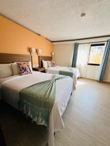 a hotel room with two beds and a window at Suites del Jardín Principal in Guanajuato