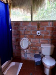 a bathroom with a toilet and a urinal in a brick wall at Sinchi Warmi Amazon Lodge in Puerto Misahuallí