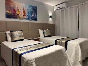 a bedroom with two beds with white sheets and a painting at AREIA DE TAPERAPUAN - 200 MTS da PRAIA - ORLA NORTE in Porto Seguro +23 photos