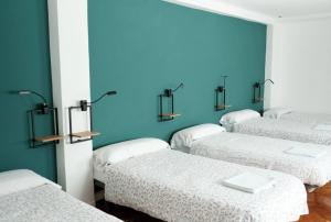 a room with four beds with a blue wall at BaruHaus GRUPOS Rua Legio in León