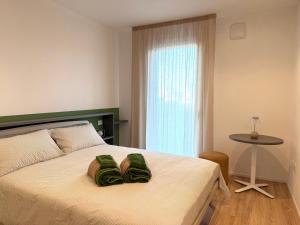 a bedroom with a bed with two green pillows on it at LA TERRAZZA APARTMENTS - Sand & Green Apartments - DeltadelPo in Porto Viro