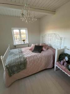 a bedroom with a bed with pink sheets and a chandelier at Romantisk bondehus in Strandby