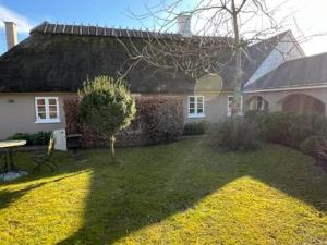 a house with a grass yard in front of it at Romantisk bondehus in Strandby