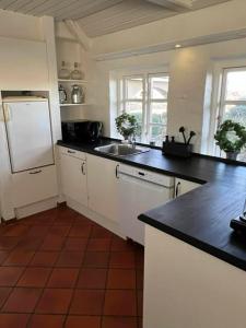 a kitchen with black counter tops and a white refrigerator at Romantisk bondehus in Strandby