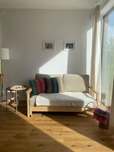 a couch sitting in a living room next to a window at Skrzydła Biebrzy- Eco Cottage nad rzeką Narwią - Biebrza NP in Niwkowo