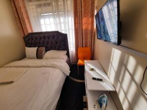 a small bedroom with a bed and a television at Goodlife Studio - NRS Kinoo in Rungiri