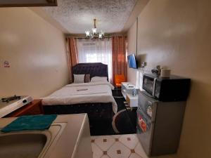 a small room with a bed and a microwave at Goodlife Studio - NRS Kinoo in Rungiri