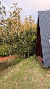 a house with a grey roof next to a field at Cabana de Vidro - Canelinha in Canelinha