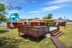 a group of huts with a pool and a deck at Oluhle Resort in Hammanskraal
