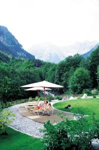 due persone sedute in sedie sotto un ombrellone di Walliserhof a Brand
