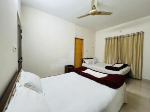 a bedroom with two beds and a ceiling fan at Tourist Home in Ābdullāpur