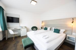 a bedroom with a large white bed and a desk at Hotel Am Martinsberg in Andernach