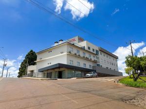 a white building with a car parked in front of it at Hotel Essência Campo Erê in Campo Erê