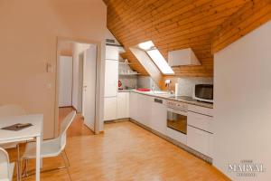 cocina con armarios blancos y techo de madera en Les Galeries Marval, en Neuchâtel