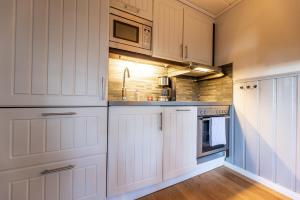 a kitchen with white cabinets and a sink at Gula Byn 410 in Sälen