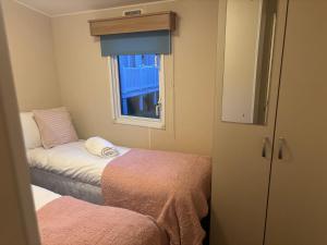 a small room with two beds and a window at Moonstone Costal Caravan Retreat in Saint Margaretʼs at Cliffe
