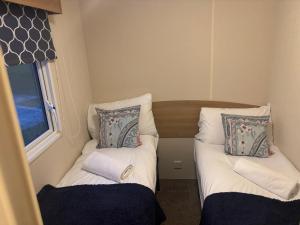 a small room with two beds and a window at Moonstone Costal Caravan Retreat in Saint Margaretʼs at Cliffe
