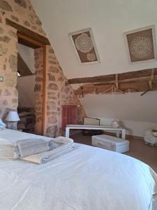 a bedroom with a bed and a stone wall at Maison la Bambine chambre nature in Ozolles