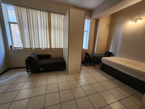 a room with a bed and a chair and a window at Ben's Place in Pretoria