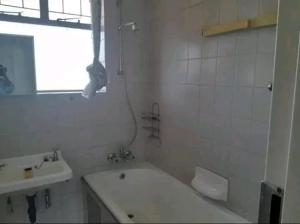a white bathroom with a sink and a bath tub at Ben's Place in Pretoria